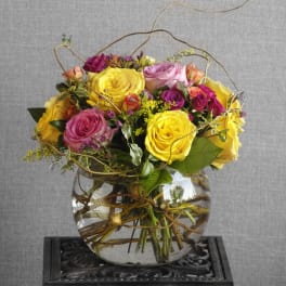 Mixed roses in a clear glass vase with curly branches