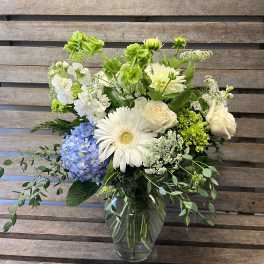 Mixed white and blue flowers arranged in a clear glass vase