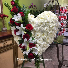 Heart-shaped white floral arrangement with red roses and white lilies