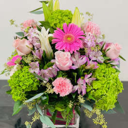 Pink and white mixed flower arrangement with bright green hydrangeas in a vase