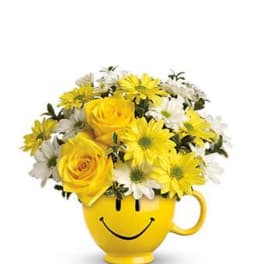 Yellow smiley-face mug filled with yellow and white flowers