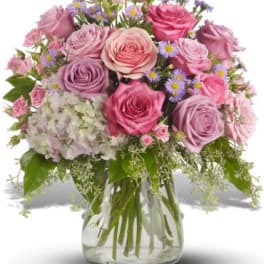 Pink and lavender roses in a glass vase with small purple daisies