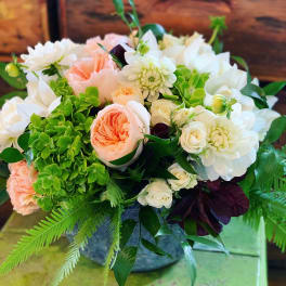 Mixed bouquet of peach, white, and green flowers in a vase