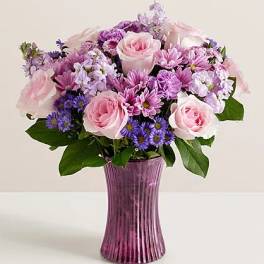 Pink and purple mixed bouquet in a purple glass vase