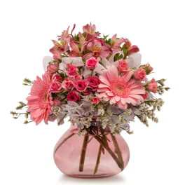 Pink gerbera daisies and roses in a pink glass vase