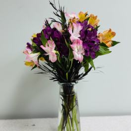 Bouquet of purple, pink, and orange flowers in a clear glass vase