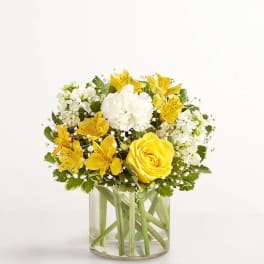 Yellow and white flower arrangement in a clear glass vase