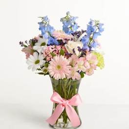 Mixed pastel bouquet in a clear glass vase with a pink ribbon