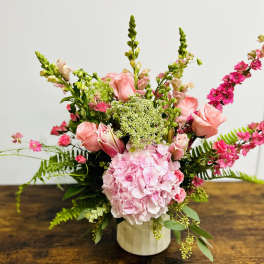 Pink floral arrangement in a white vase with tall spiky blooms