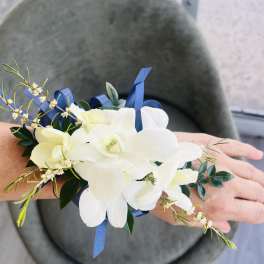 White orchid wrist corsage with blue ribbon accents