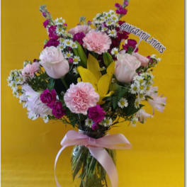 Mixed pink and white flowers in a glass vase with a congratulations sign