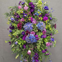 Large standing floral spray with purple, pink, blue, and green blooms