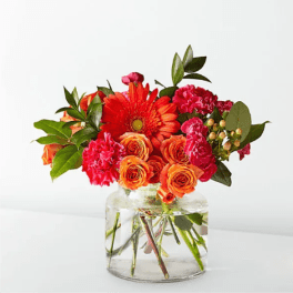 Orange and pink mixed bouquet in a clear glass vase