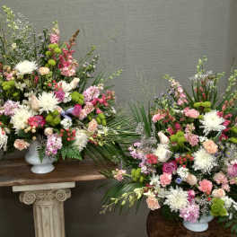 Two large mixed flower arrangements in white urns
