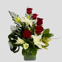 Red roses and white lilies arranged in a glass vase