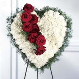 Heart-shaped floral spray with red roses and white flowers on a stand