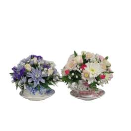 Two mixed flower arrangements in teacups on saucers