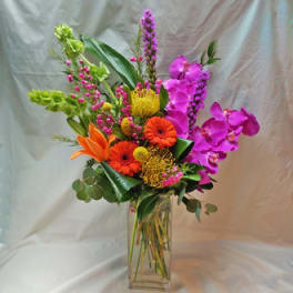 Bright mixed bouquet in a clear glass vase with orange, pink, and yellow blooms