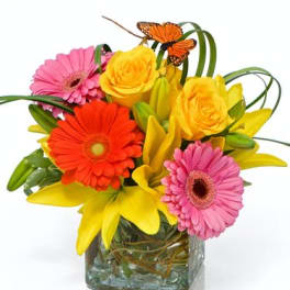 Bright mixed bouquet in a square glass vase with pink and orange daisies and yellow roses