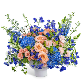 Peach roses and blue flowers in a white vase