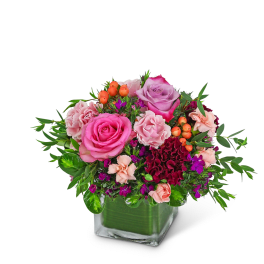 Pink and purple rose arrangement in a square glass vase