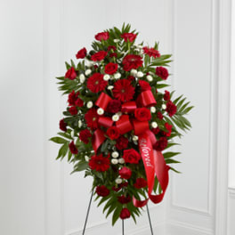 Standing floral spray of red flowers with a red ribbon on an easel