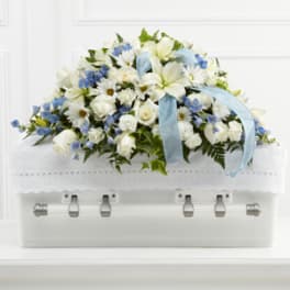 White and blue floral casket spray with a pale blue ribbon