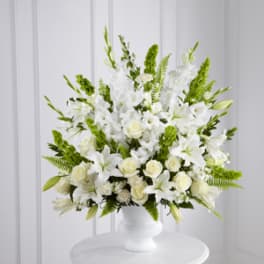 White floral arrangement in a white vase with green accents