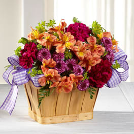 Mixed bouquet in a wooden basket with purple ribbon