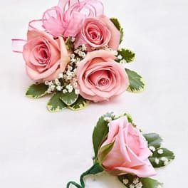 Pink rose corsage and boutonniere with ribbon and small white filler flowers