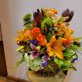 Basket arrangement with orange lilies, roses, and autumn accents