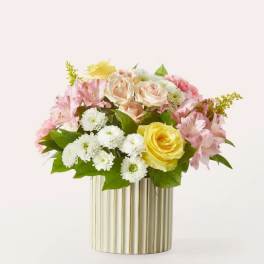 Pink and yellow flower arrangement in a gold ribbed vase