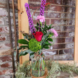 Mixed floral arrangement in a glass vase with pink and red blooms