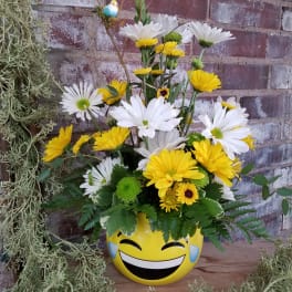 Yellow and white daisy bouquet in a smiley-face pot