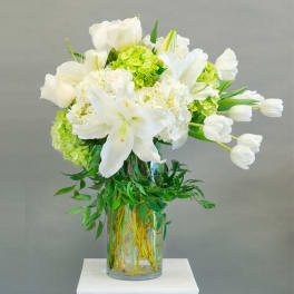 White lilies and tulips arranged in a glass vase
