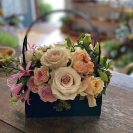 Basket of pastel roses with pink accent flowers