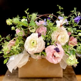 Pastel floral arrangement in a brown box with white ribbon