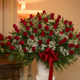 Large bouquet of red roses with white filler flowers in a white vase