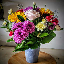 Mixed bouquet of colorful flowers in a textured white vase