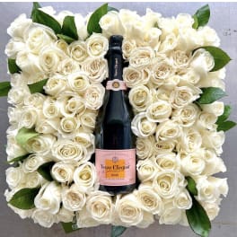 White rose arrangement surrounding a champagne bottle