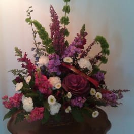 Mixed floral arrangement in a wooden basket with tall purple blooms