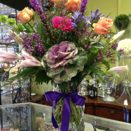 Mixed bouquet in a glass vase with a purple ribbon