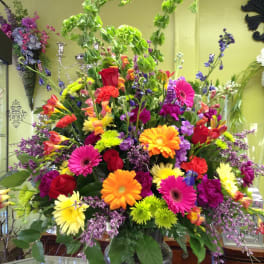 Large mixed bouquet with gerbera daisies, roses, and colorful filler flowers in a vase