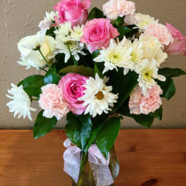 Pink roses and white daisies with pale carnations in a glass vase