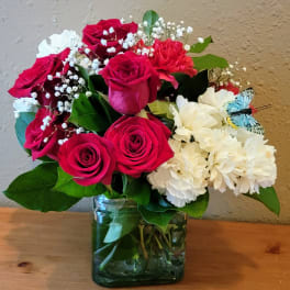 Bouquet of red roses and white carnations in a glass vase