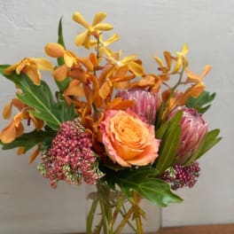 Orange and pink floral arrangement in a clear glass vase