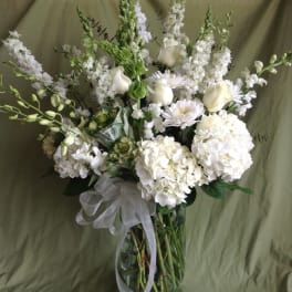 White floral arrangement in a glass vase with a sheer ribbon