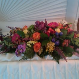 Large floral casket spray with pink, orange, purple, and white blooms