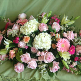 Pink roses and lilies arranged with white hydrangeas on green fabric