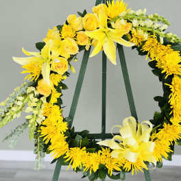Yellow floral wreath on a stand with roses and lilies